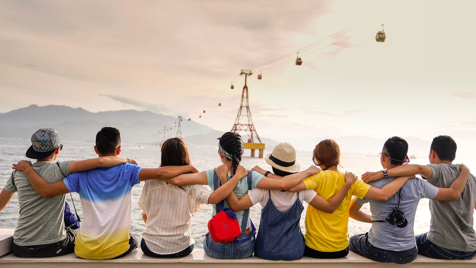 Friends with arms around each other's shoulders facing an open field